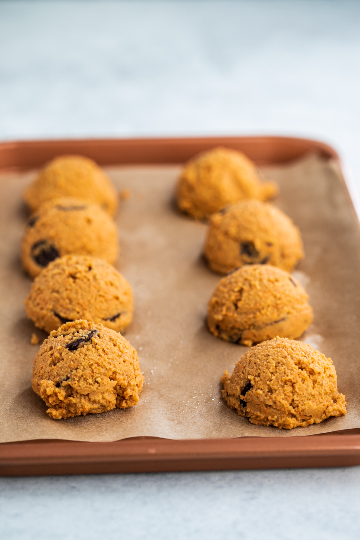 Sweet potato cookie batter in portions on a rose gold baking tray