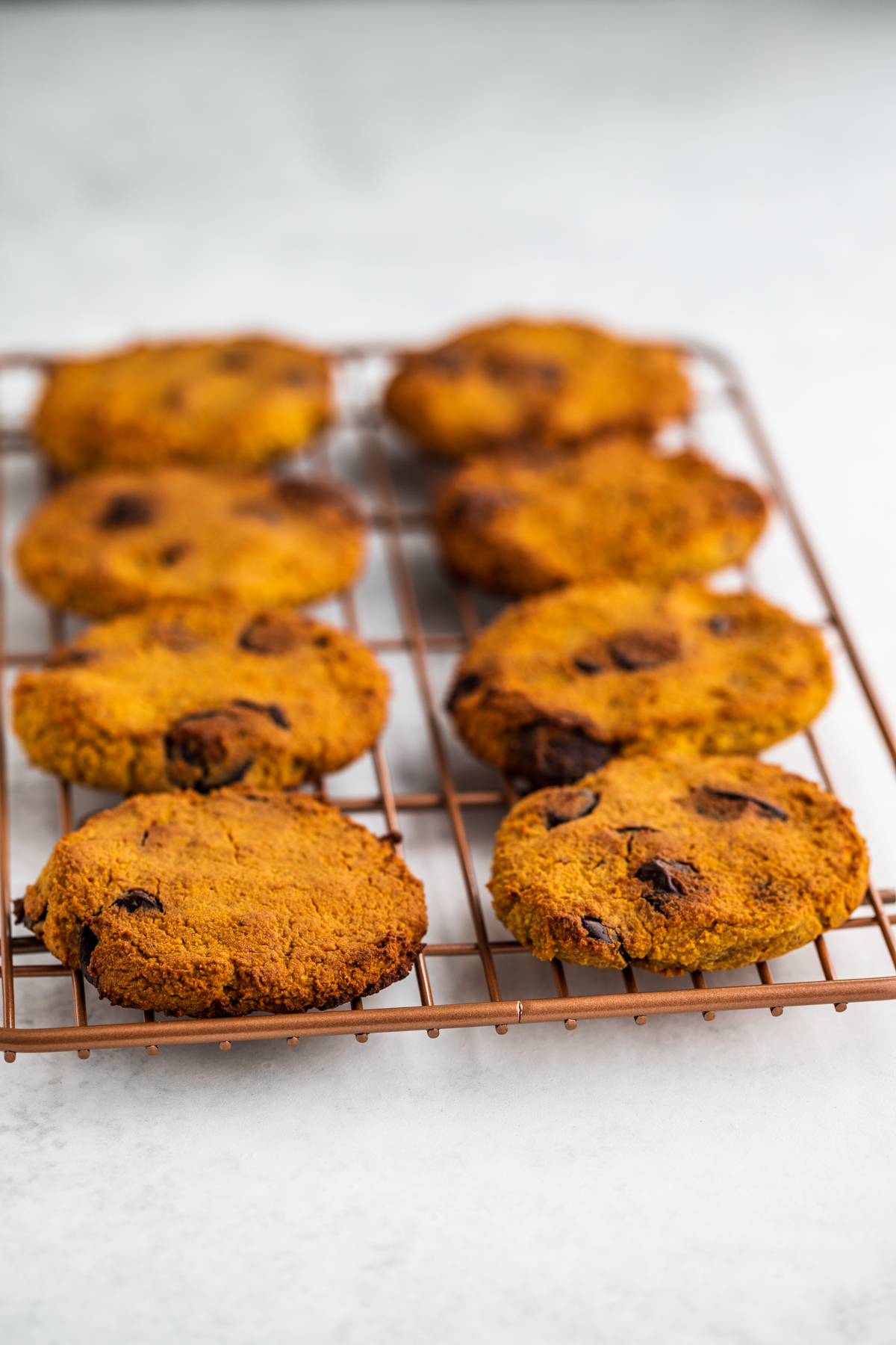Sweet potato cookies on a rose gold cooling rack on a white background