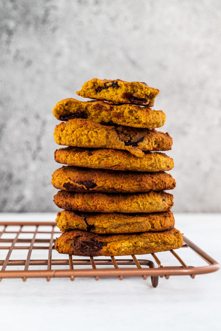 A stack of sweet potato cookies on a rose gold rack and white background