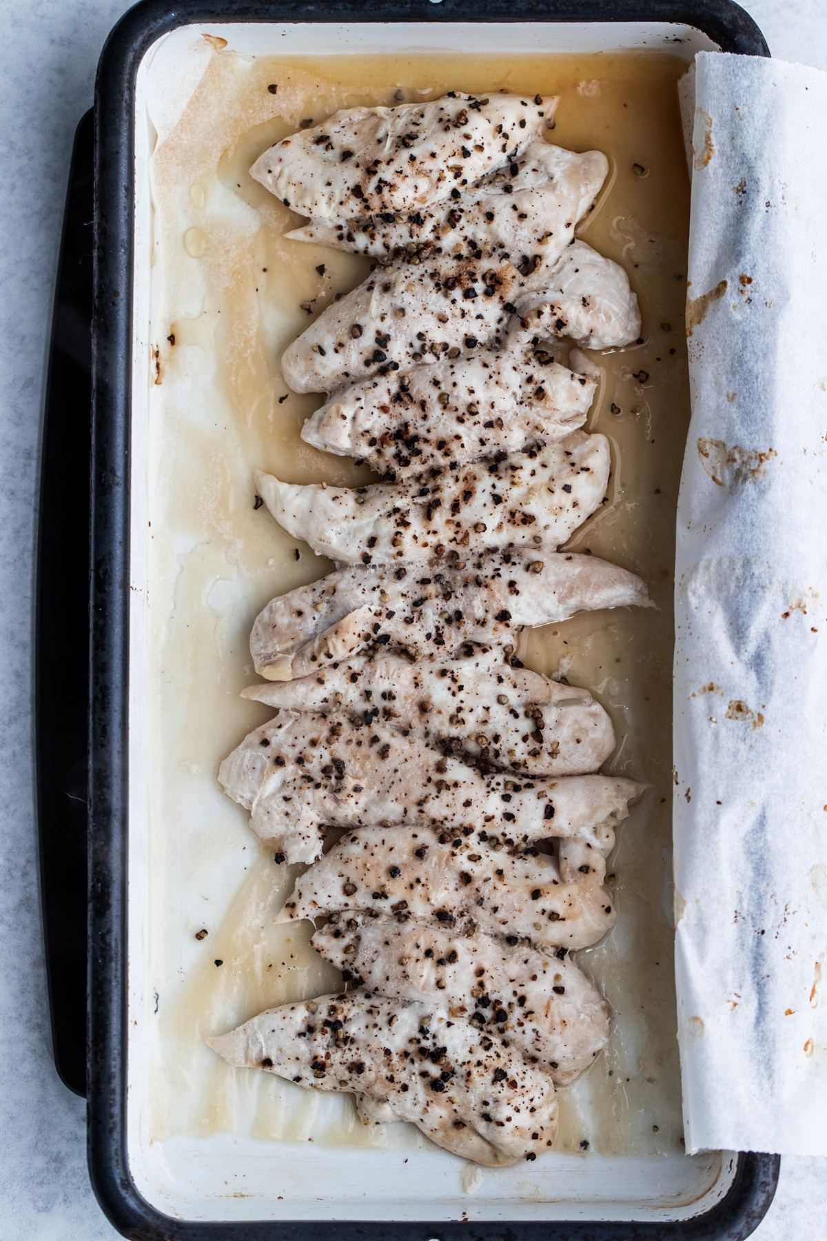 Overhead shot of cooked lemon pepper chicken breast fillets in a white baking tray