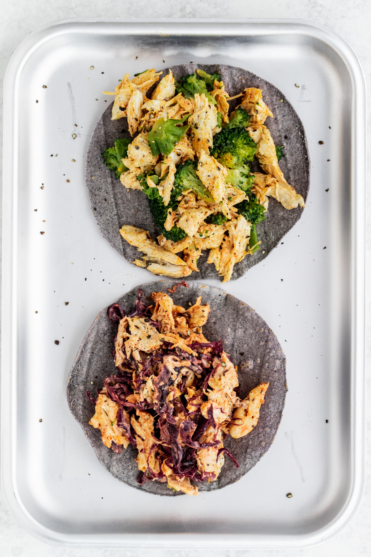 Overhead view of chicken and broccoli and sauerkraut chicken tacos on a silver serving tray