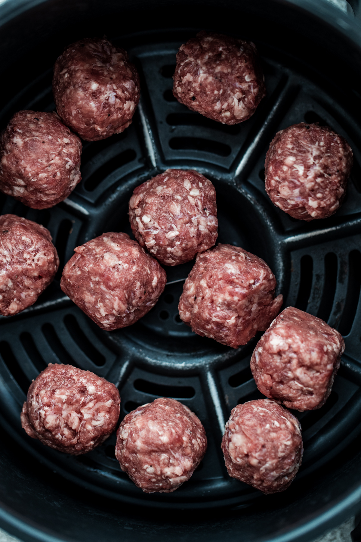 Overhead shot of meatballs in an air fryer before being cooked