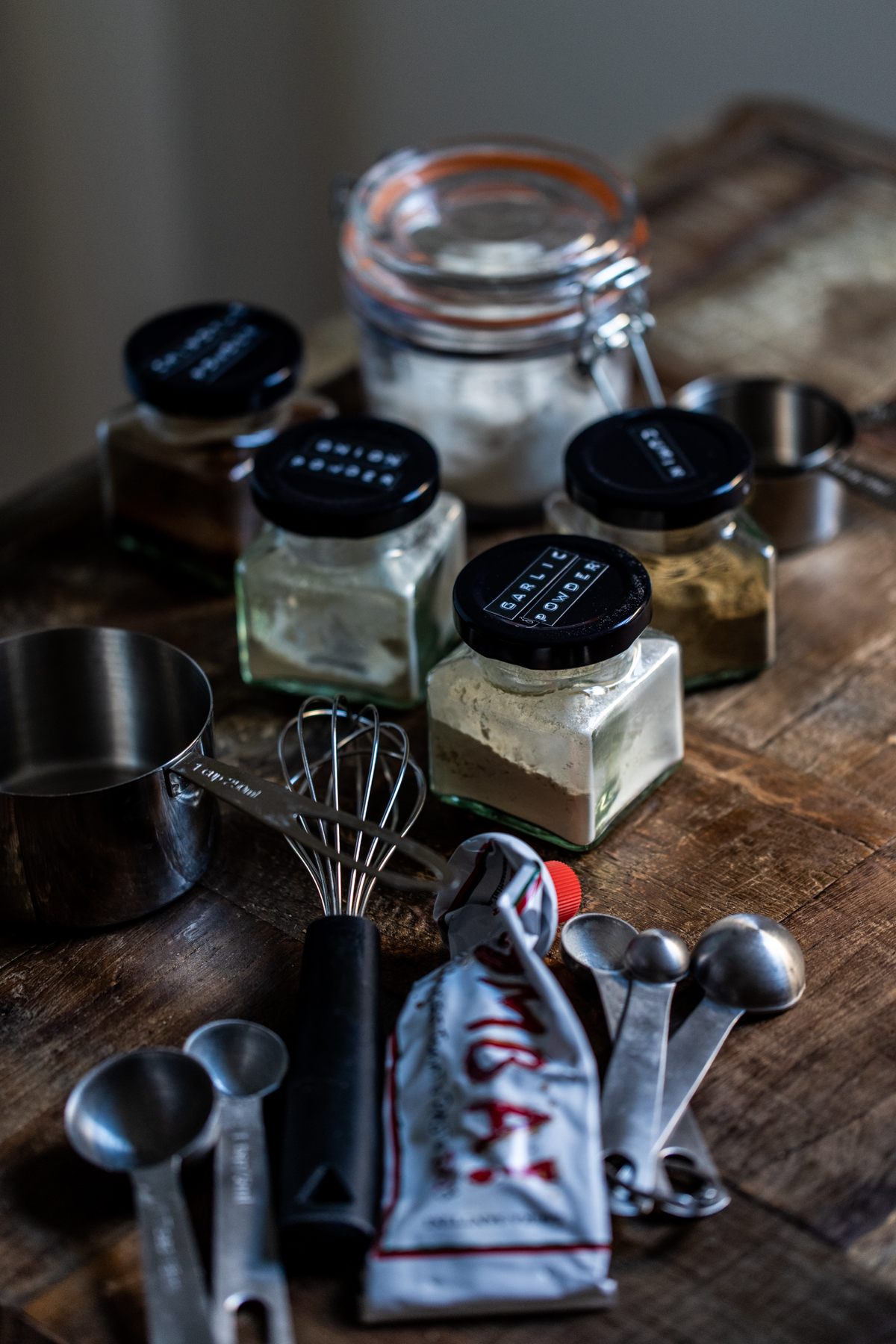 Jars of ingredients for slow cooked chipotle chicken on a table with some kitchen utensils 