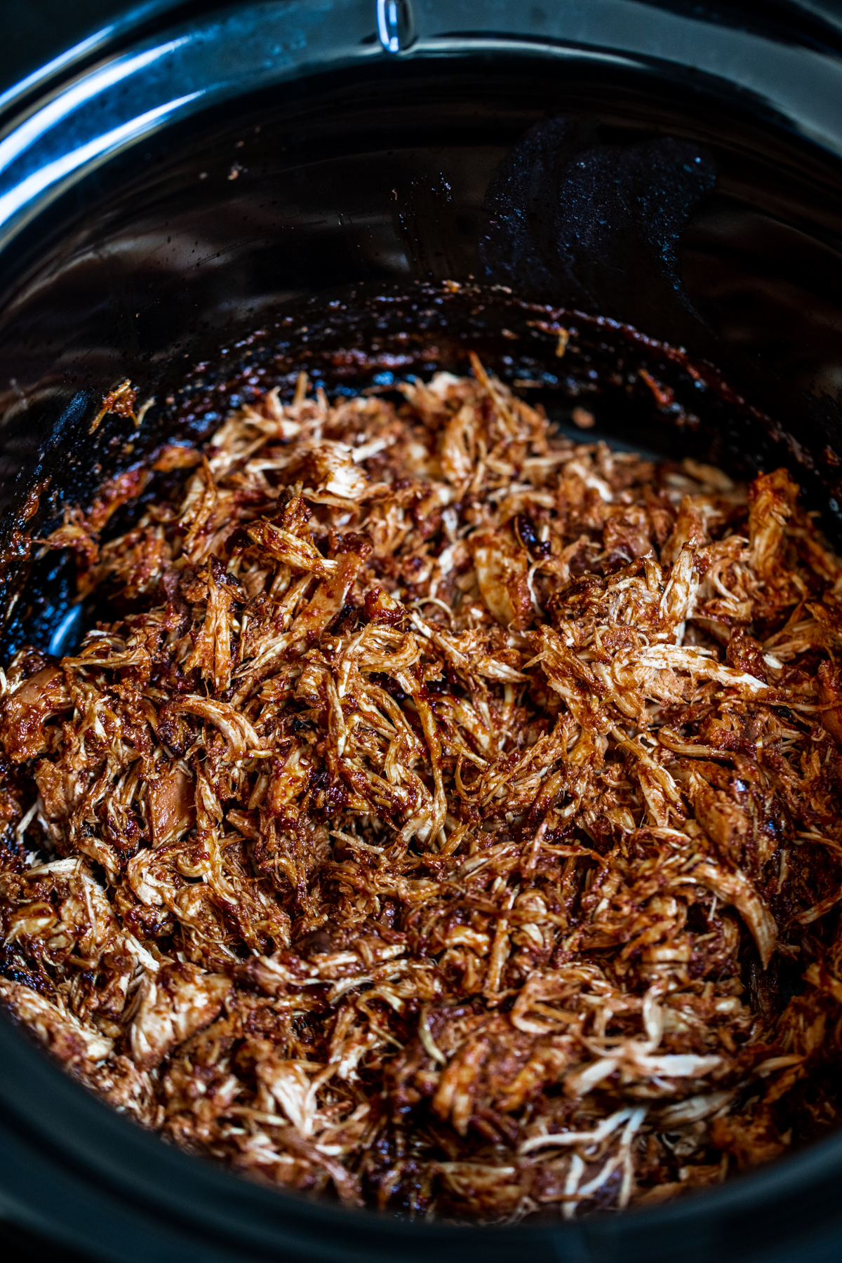 Shredded slow cooked chipotle chicken breast in the slow cooker after being shredded