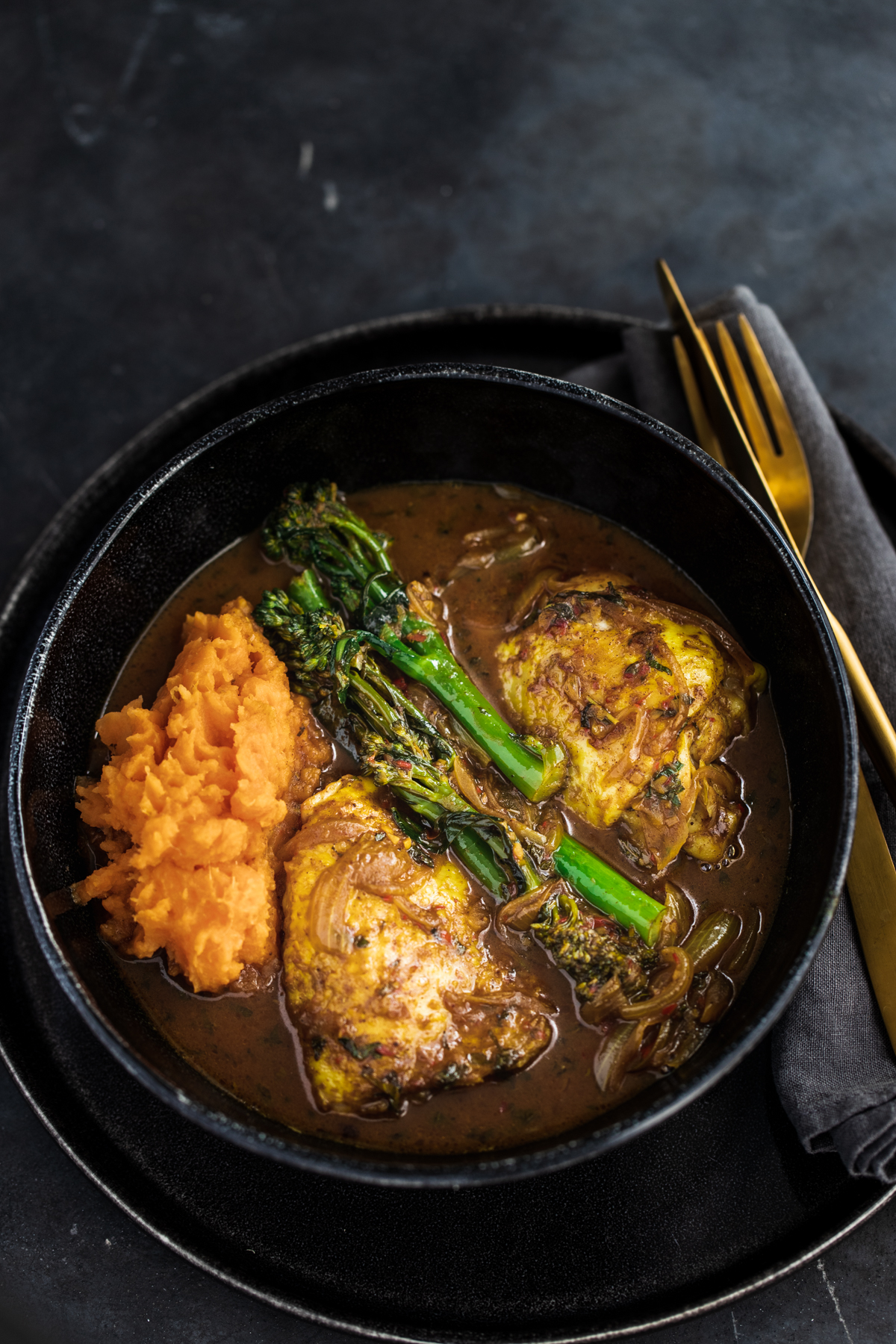 Malaysian Chicken Thigh Curry with broccoli and sweet potato in a black bowl