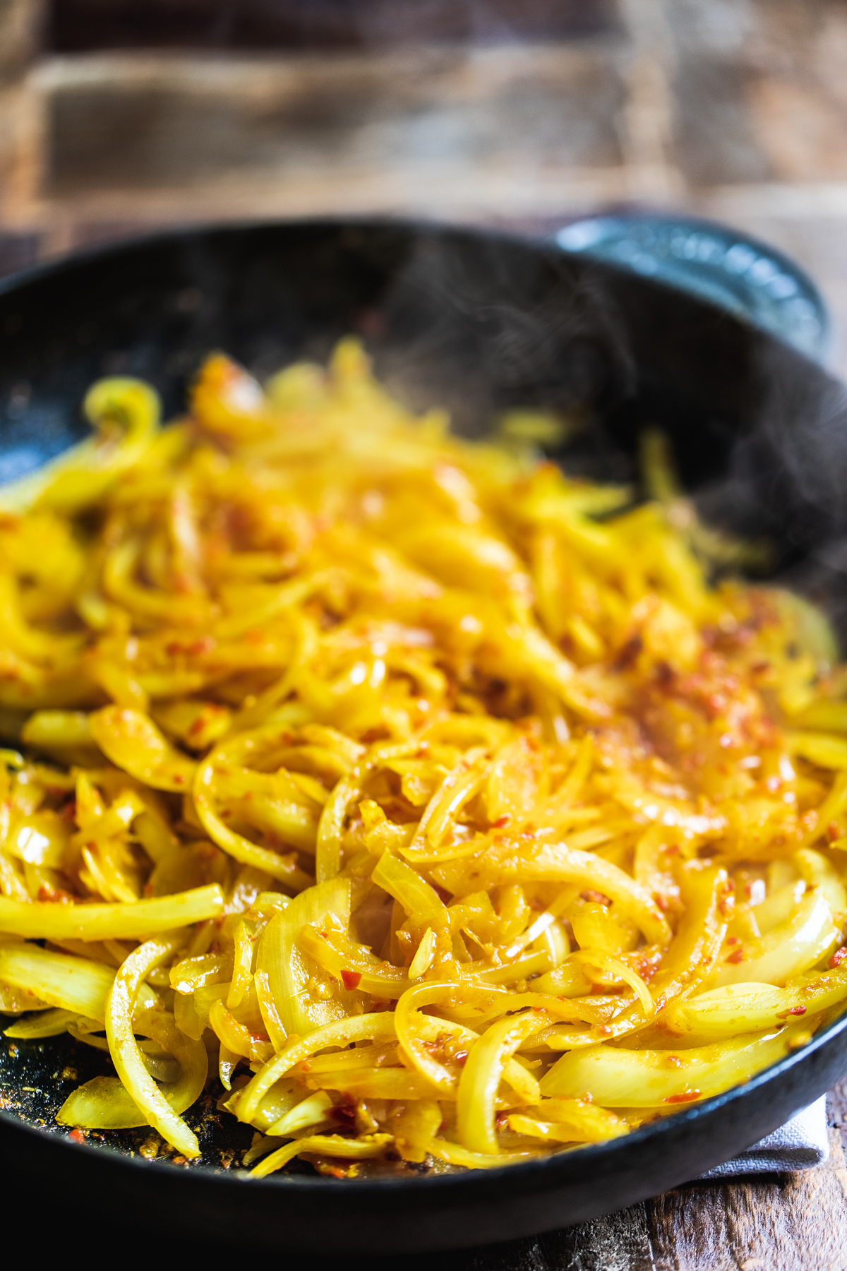 Onions & Malaysian curry paste cooking in a black cast iron pan.