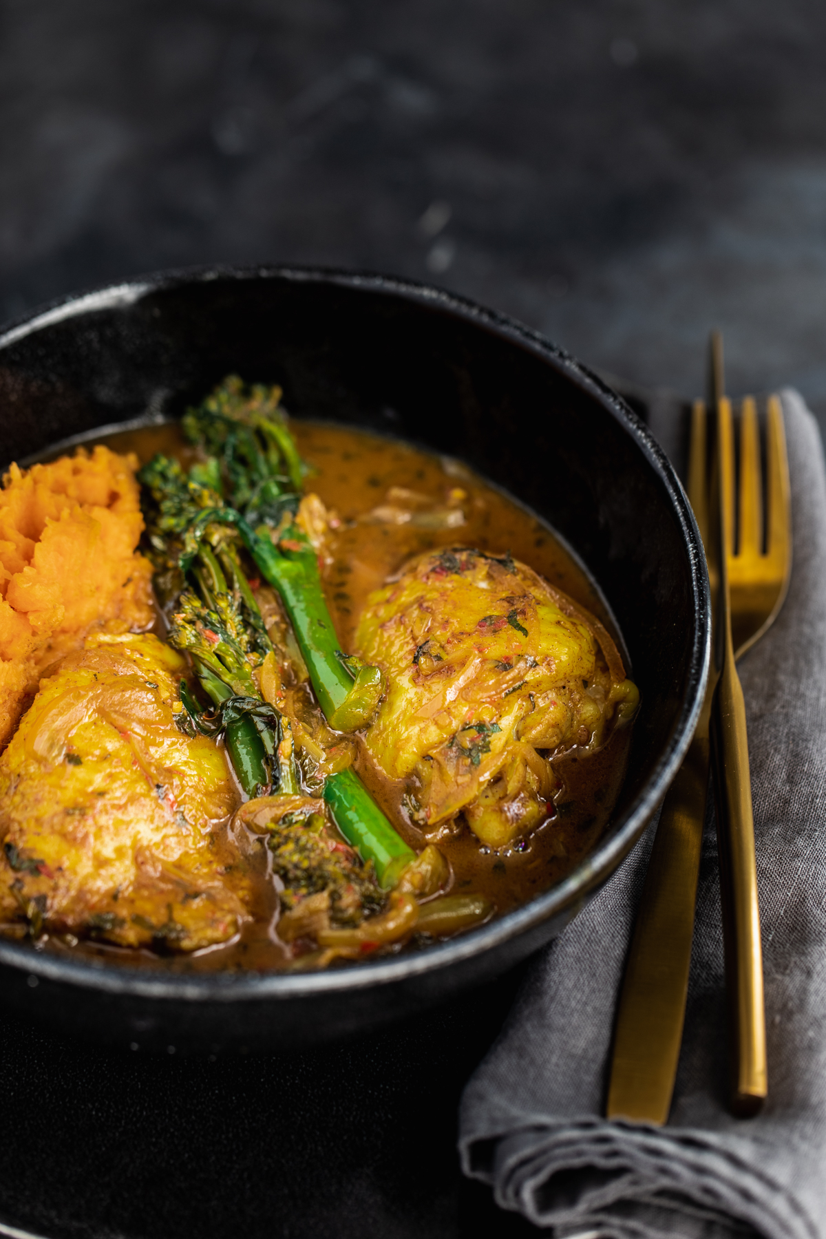 Malaysian Chicken Thigh Curry with broccoli and sweet potato in a black bowl