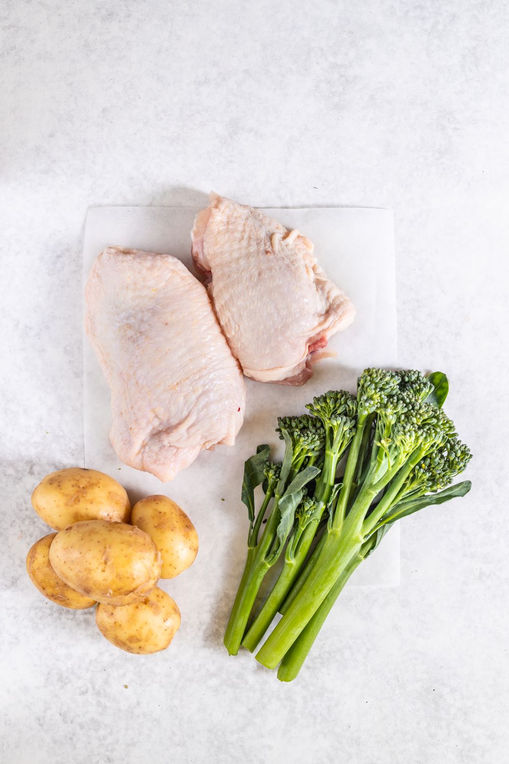 One pot slow cooked chicken thighs potato and broccoli in a bowl on a white background