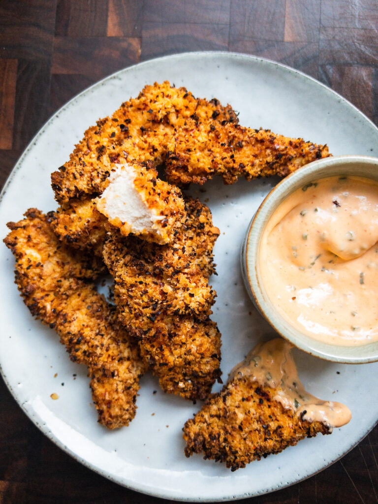 Air fryer crispy chicken tenders on a blue plate with sriracha mayo