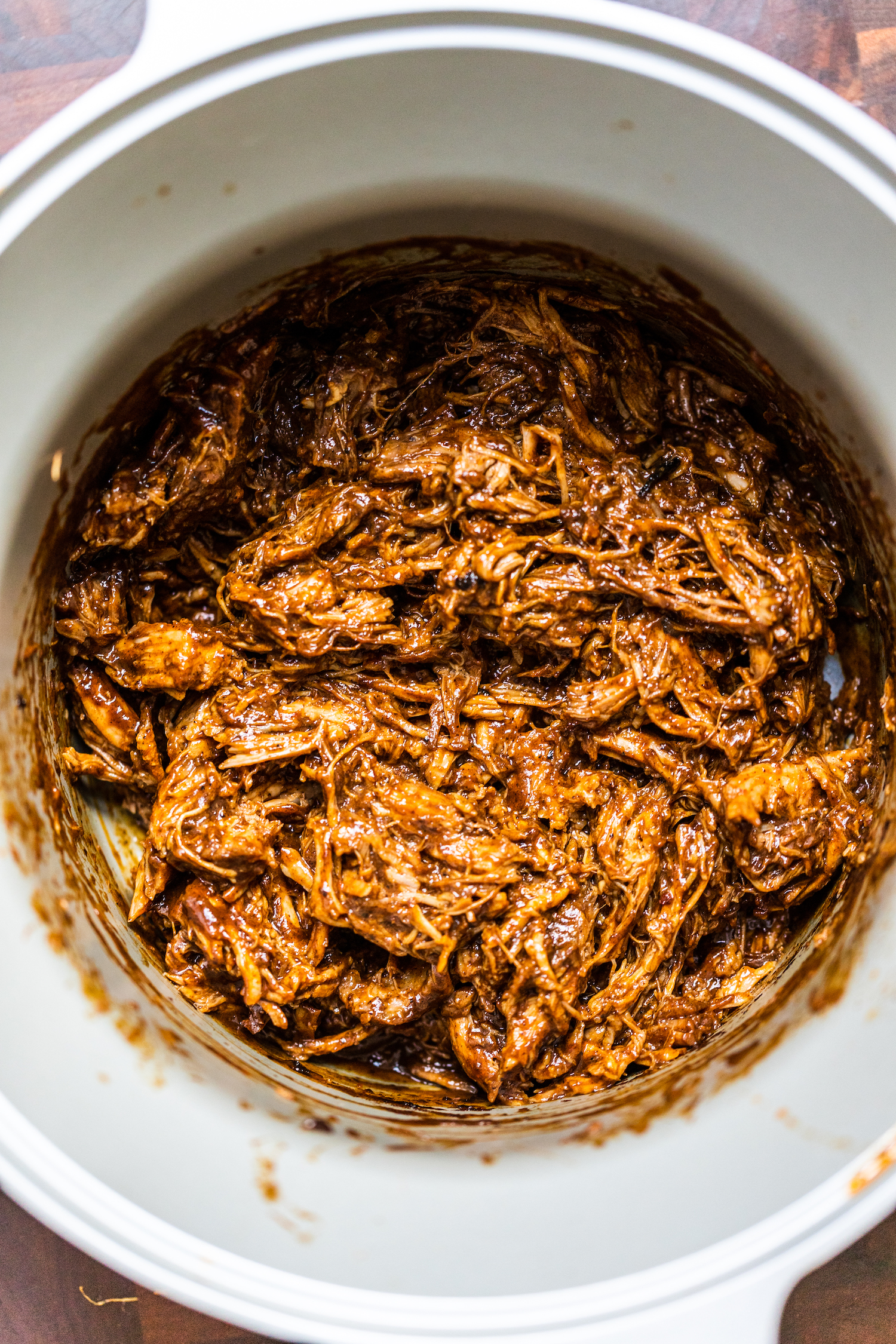Smoky pulled pork in a slow cooker on a wooden board