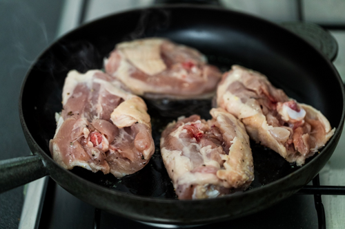 Searing skin-on chicken thighs in a cast iron pan