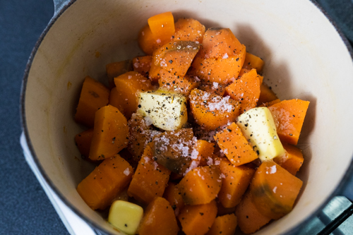 Boiled sweet potato with salt, pepper and butter in a pot before being mashed