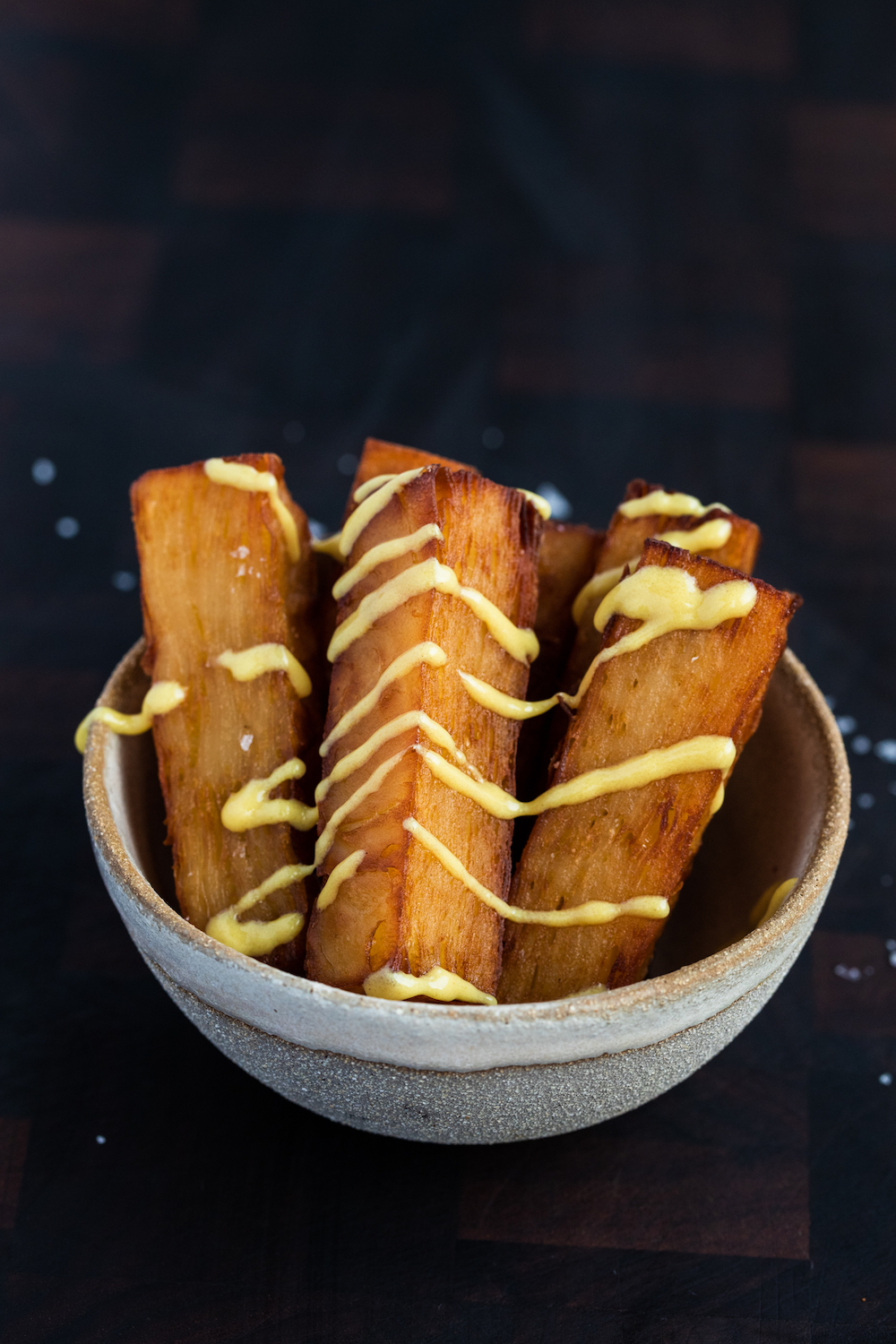 Quality Chop House confit potatoes with mustard dressing in a bowl on a wooden board