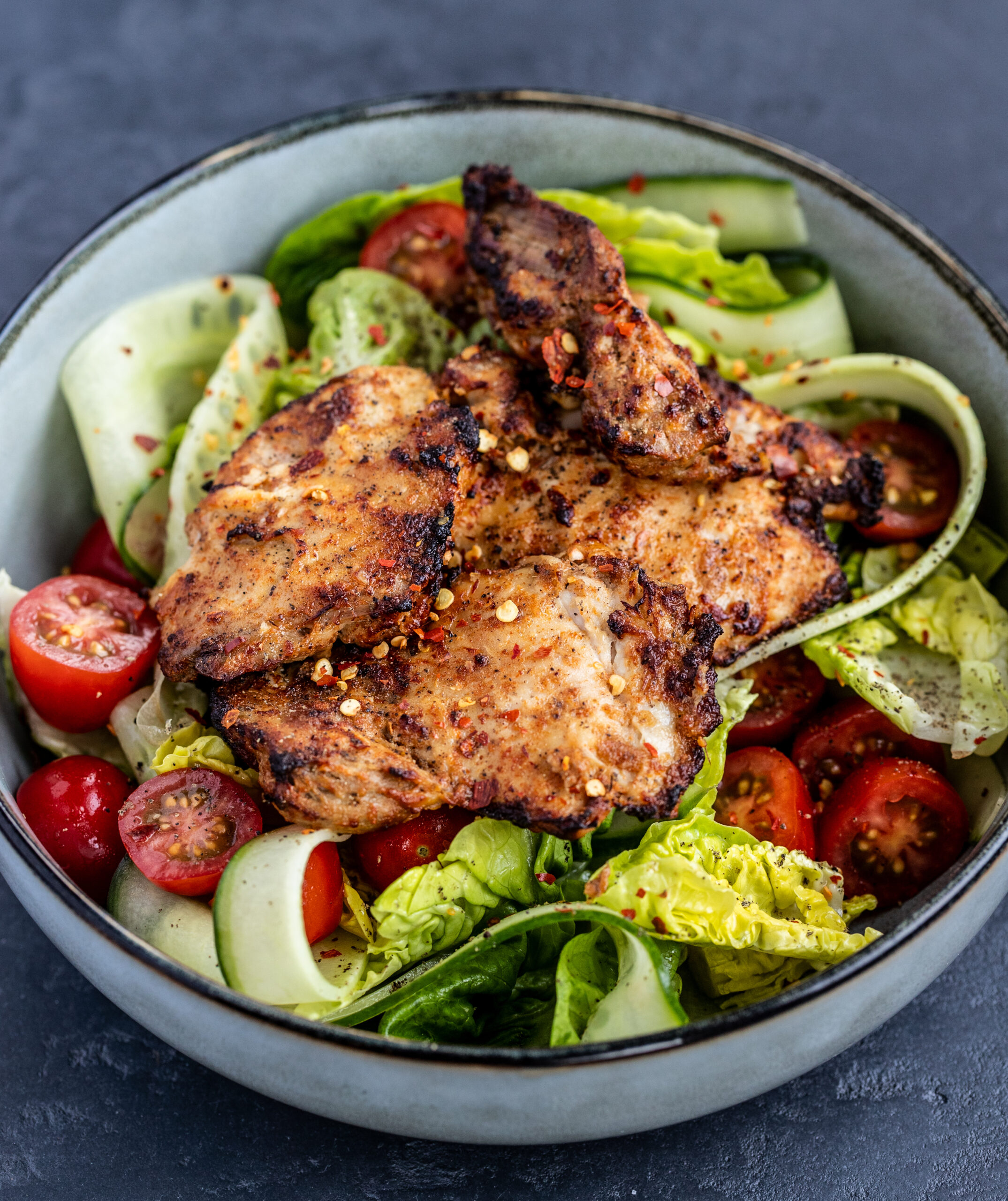 Air fryer tandoori chicken on top of salad served in a grey bowl