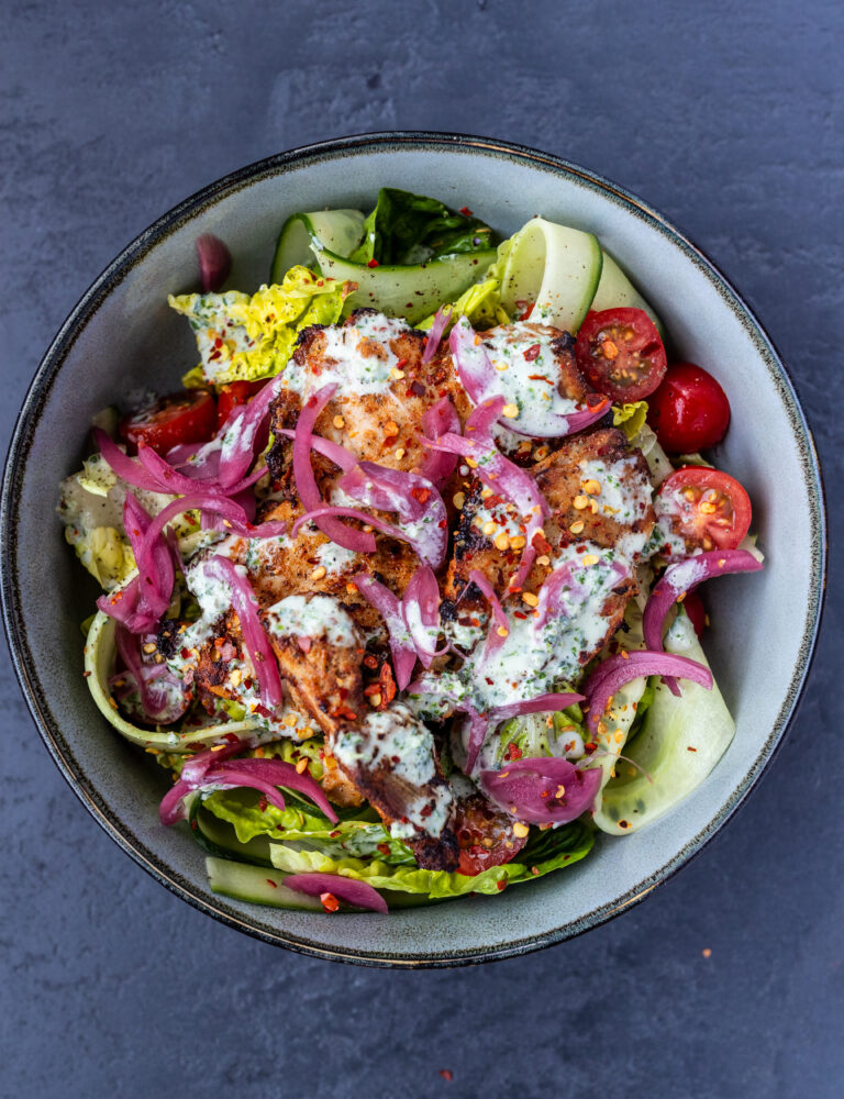 Air fryer tandoori chicken in a blue bowl with salad and coriander cream sauce dressing