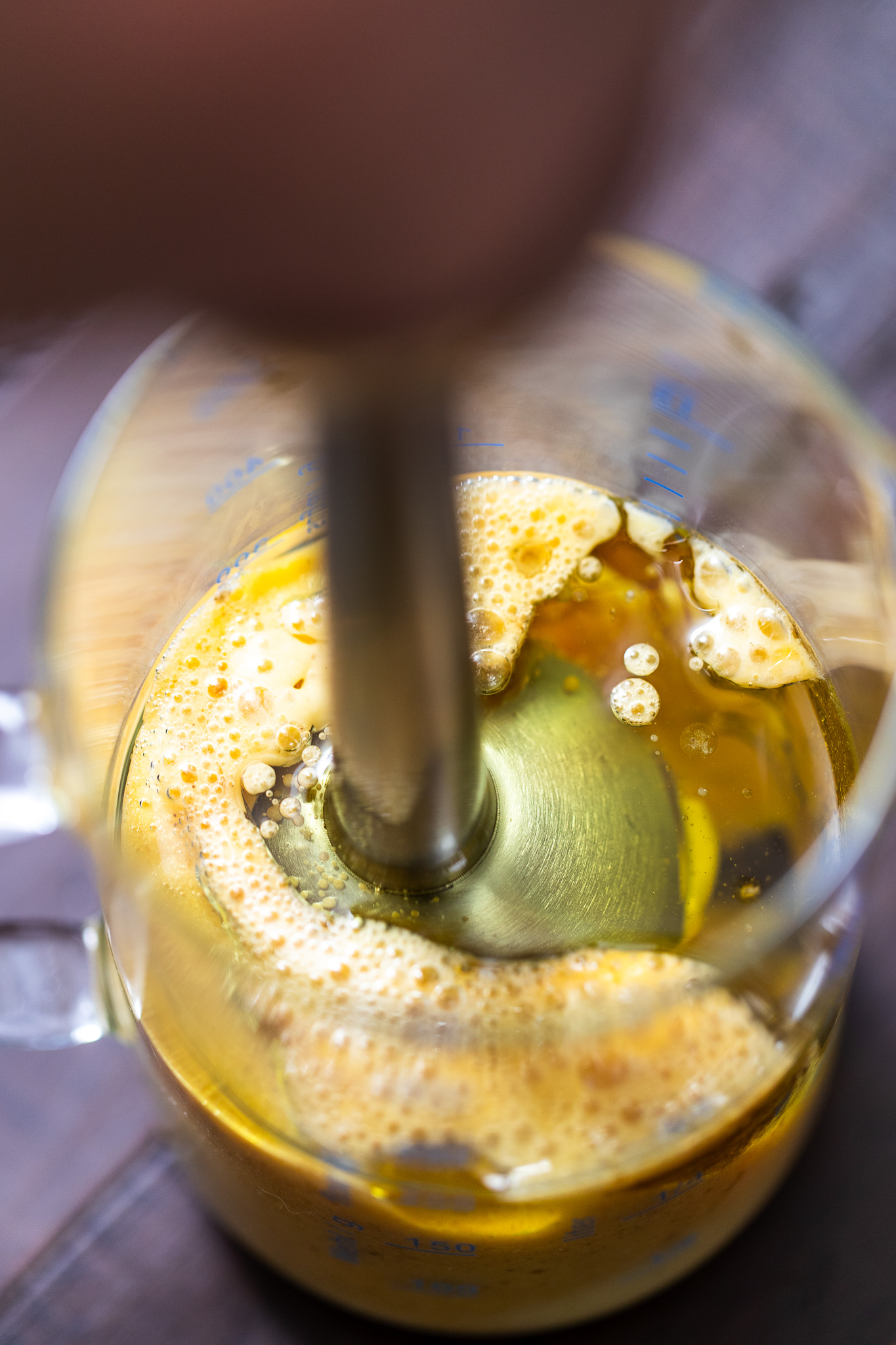 Overhead shot of a stick blender going into mayo ingredients in a jug, about to be blended