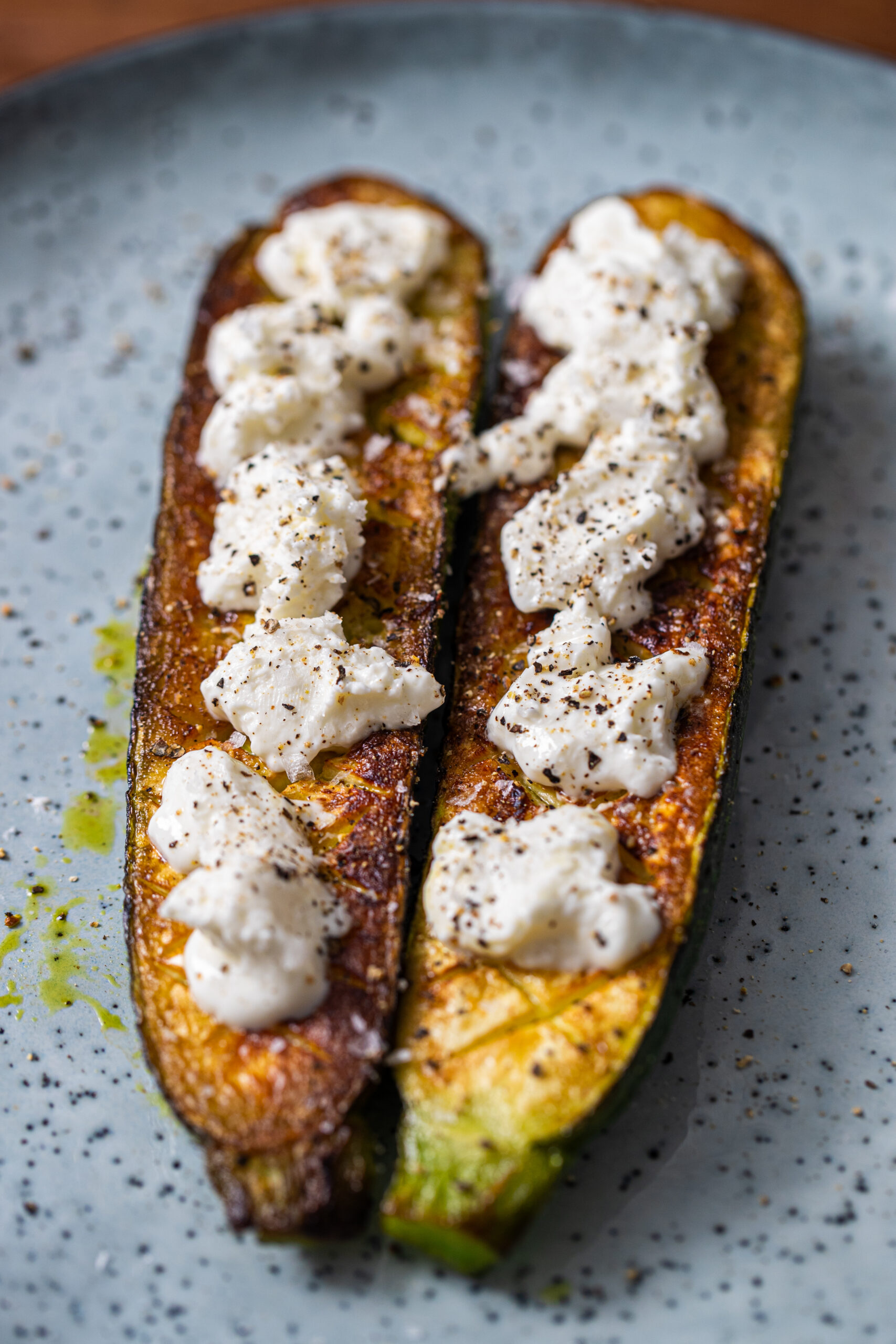 Viral Thomas Keller zucchini on a blue plate topped with goat cheese and black pepper.