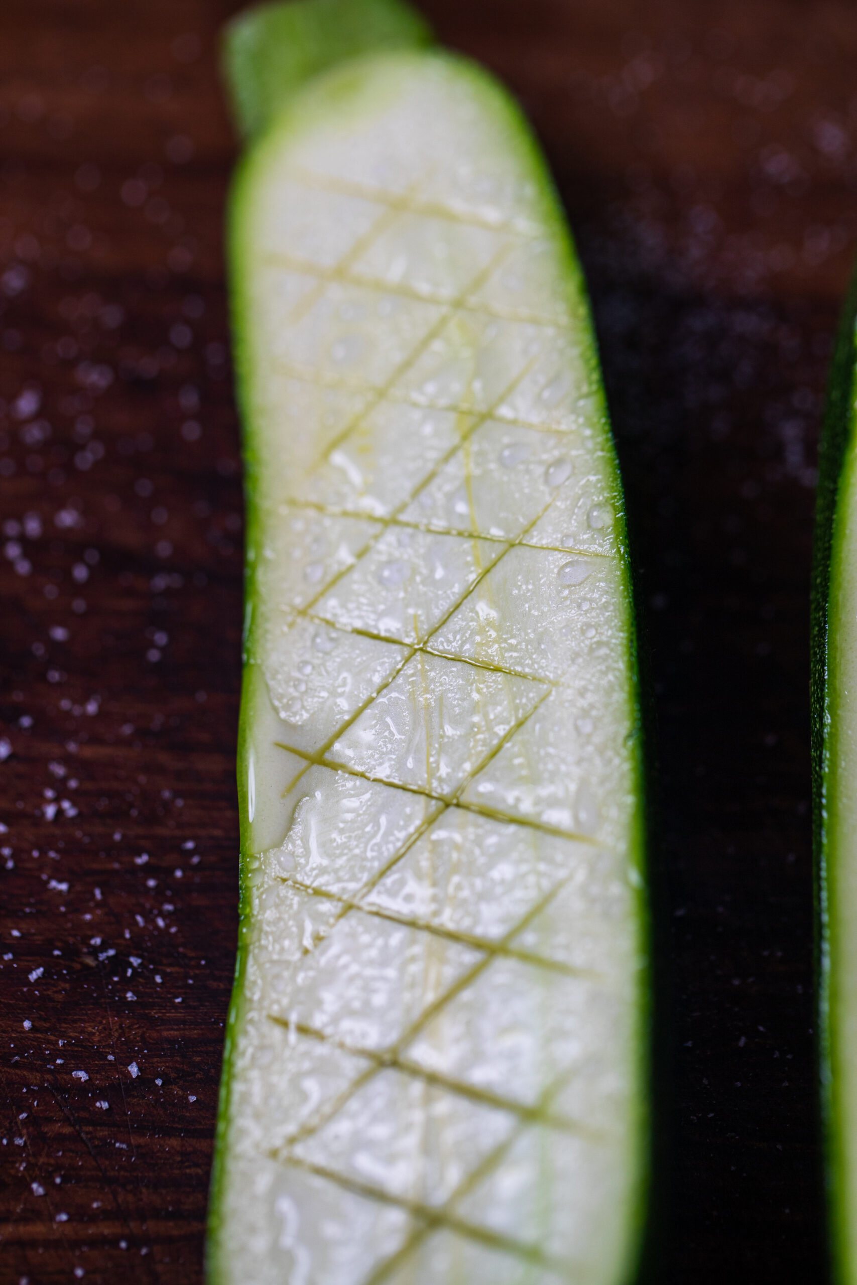 A salted zucchini showing the moisture collecting on the surface from being salted