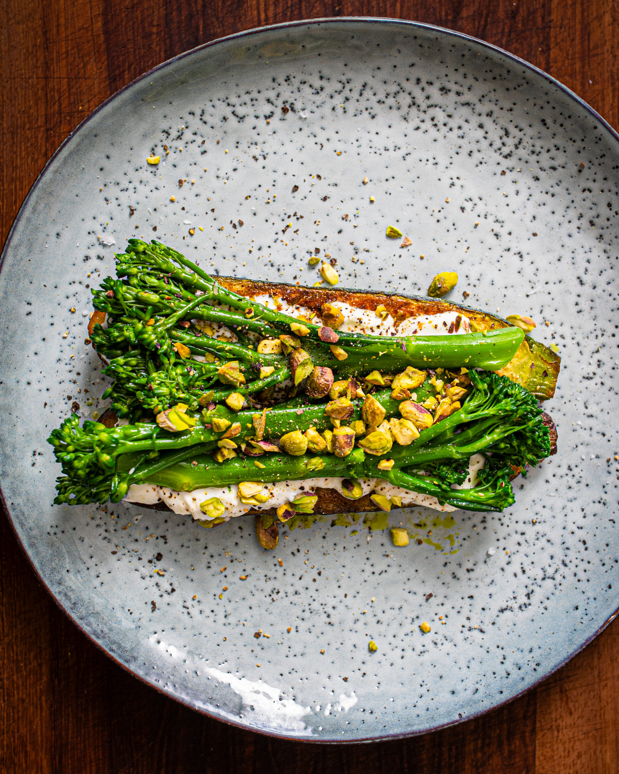 Thomas Keller zucchini dressed with goat cheese, broccoli and pistachios on a blue plate