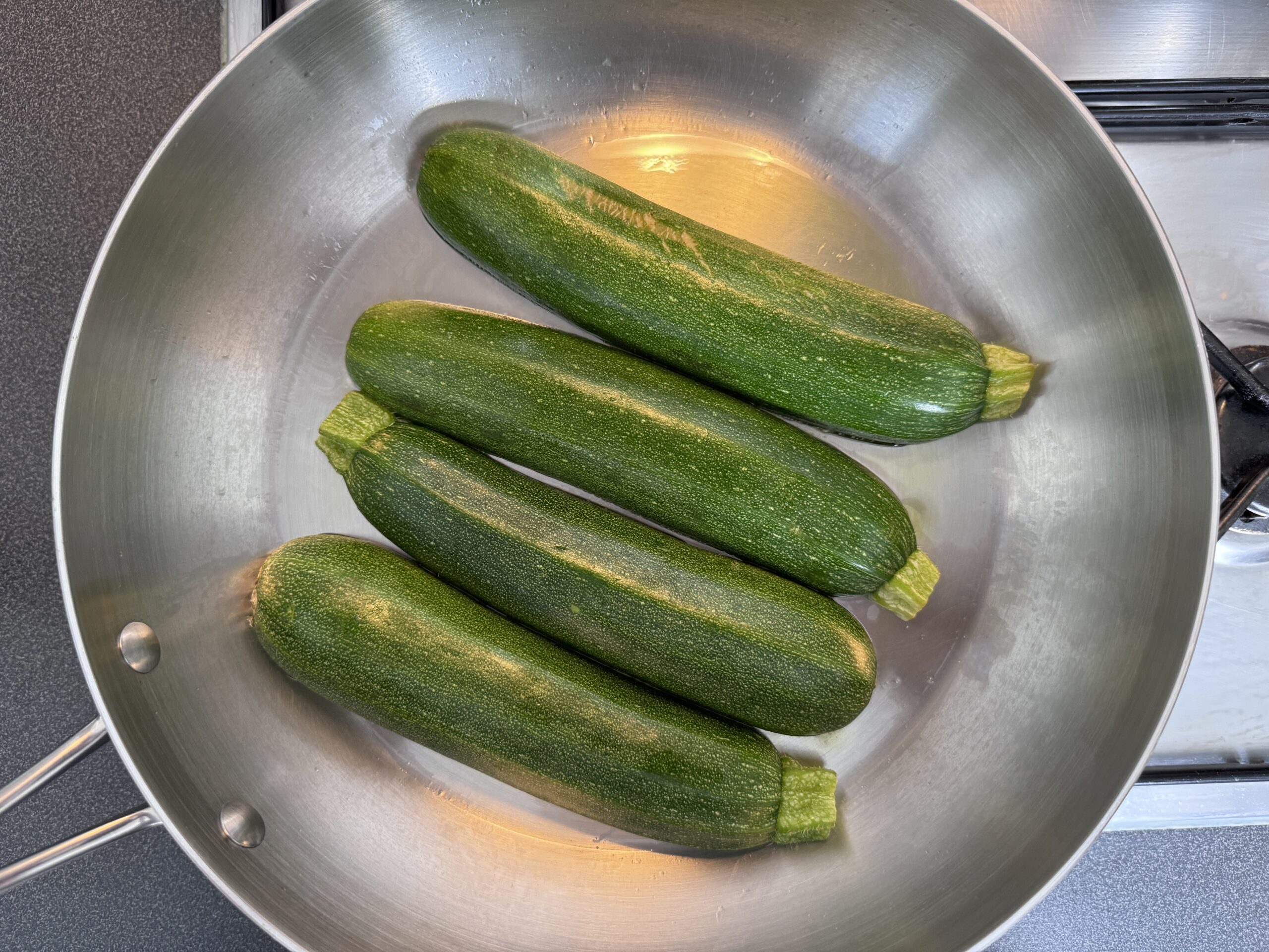 Zucchini cut side down in a stainless steel pan