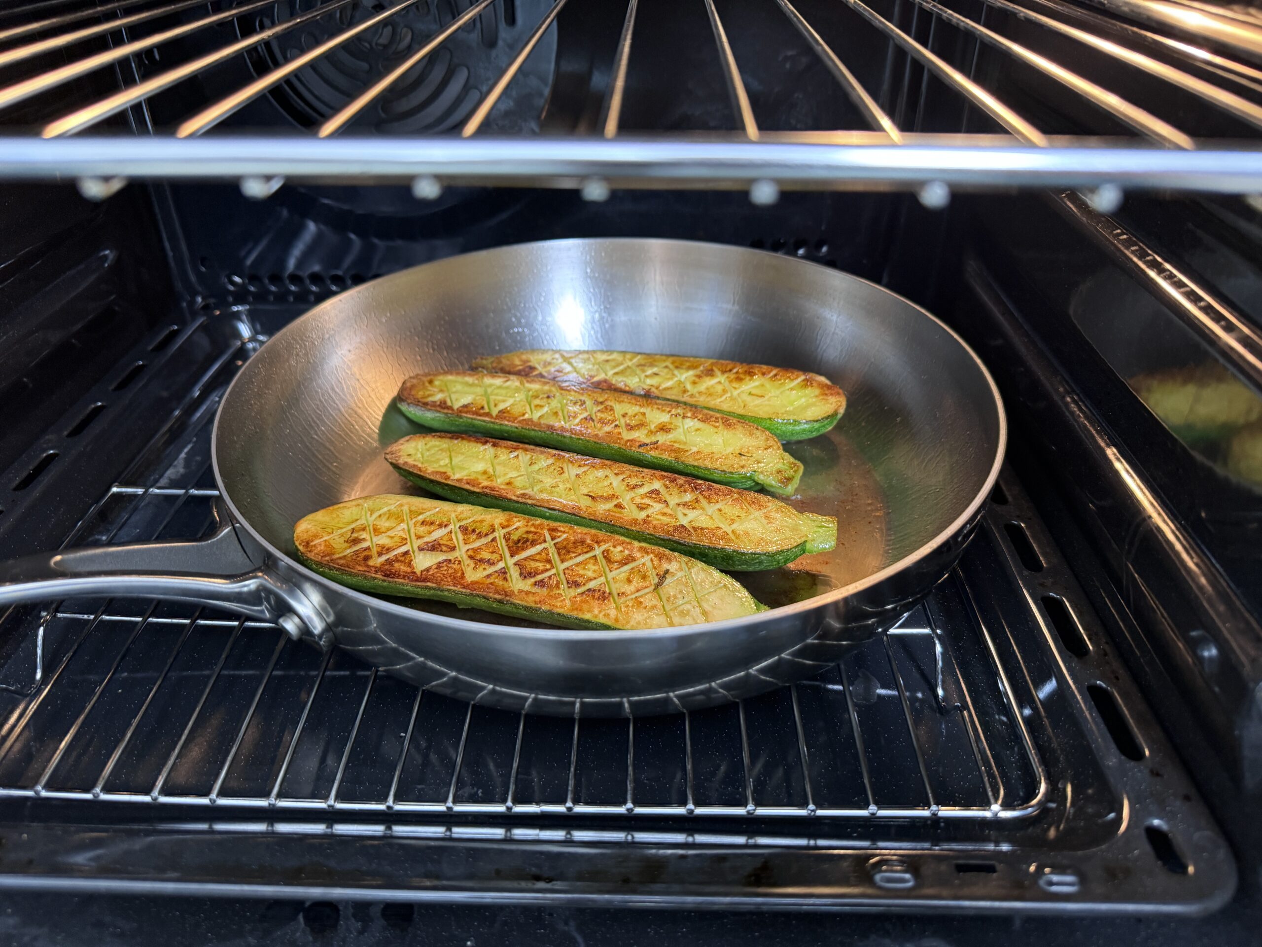 Zucchini in a stainless steel pan going into the oven